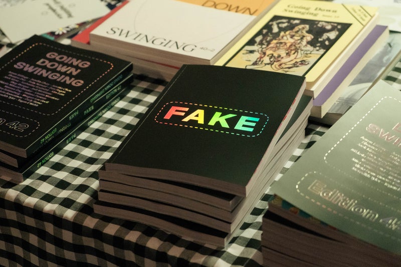 Image of FAKE edition sitting on a table with checkered table cloth surrounded by GDS back editions.