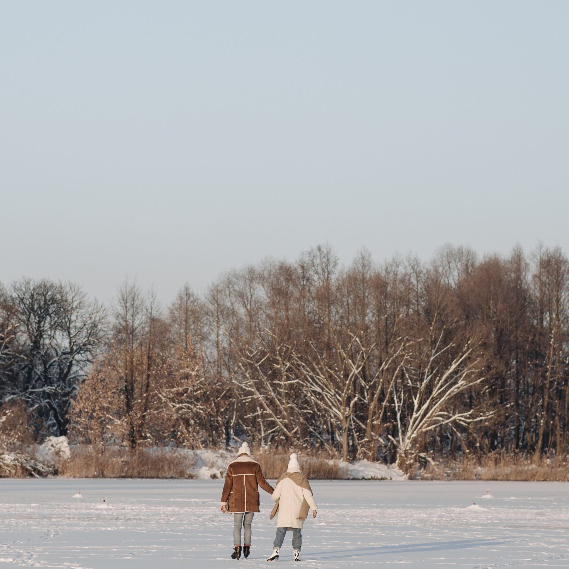 a photo of a frozen pond with two small figures ice-skating