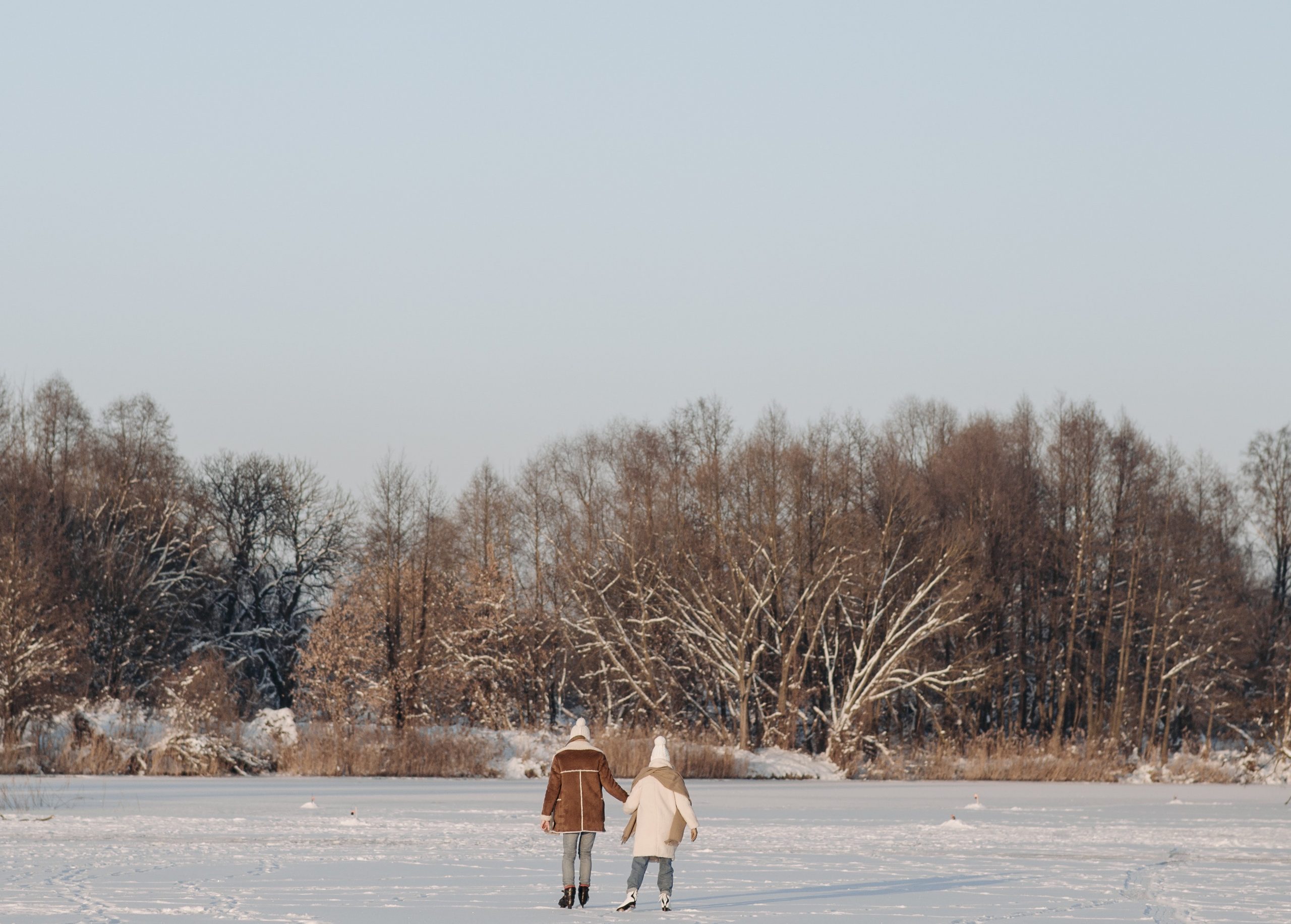 a photo of a frozen pond with two small figures ice-skating